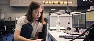 "Bad Banks - The man from London": noticeably tired and overworked, Jana (Paula Beer) sits in the office at night and works. The young woman has taken off her shoes, squats on her office chair with her legs drawn up, and looks almost apathetically at the monitors in front of her.
