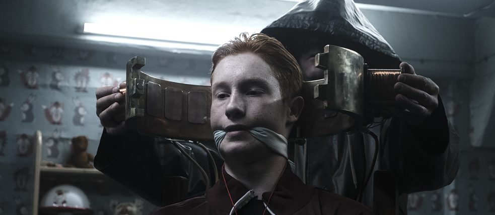 DARK - Eric Oberndorf est enchaîné et bâilloné dans un bunker, derrière lui une silhouette sombre