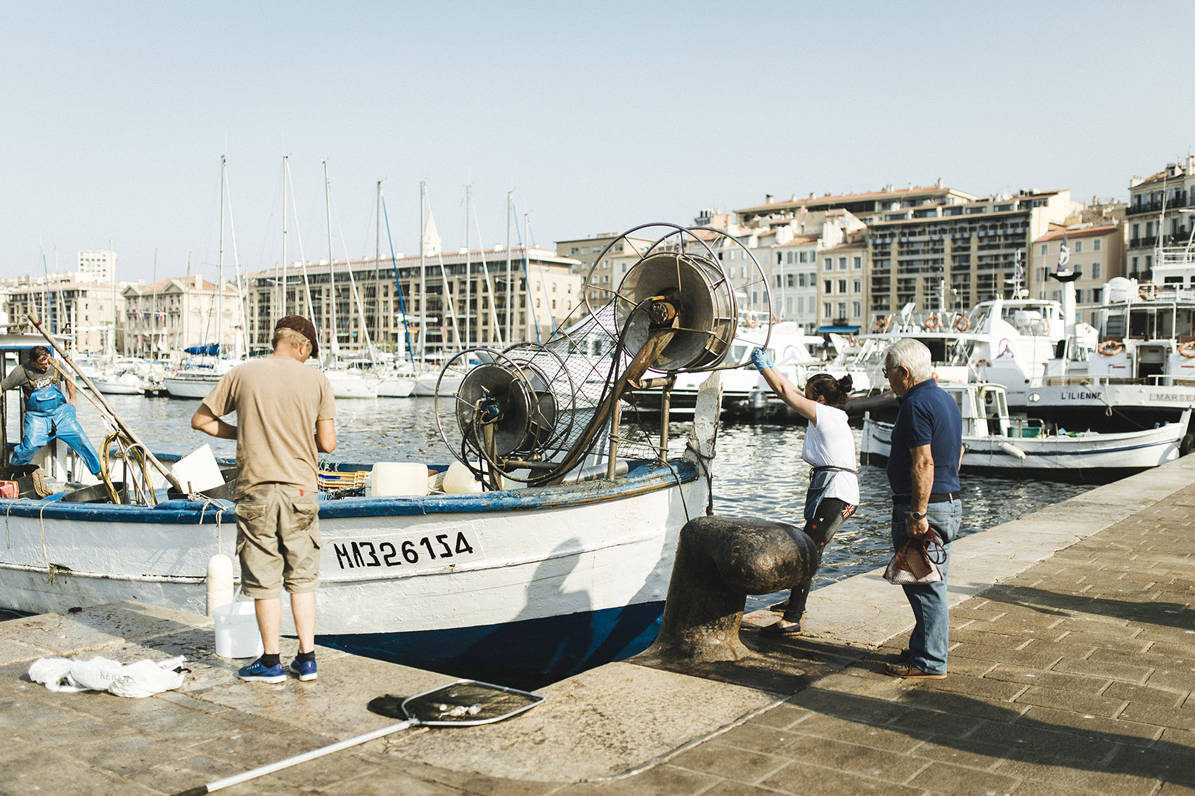Hélène legt mit dem Fischkutter im Hafen an, einige Männer stehen am Quai.