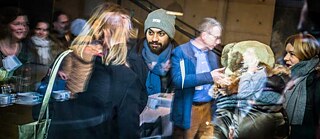 Various people at an event photographed through a pane of glass