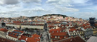 <b>Quartel do Carmo (Lissabon, Portugal)</b><br> <br>Wer die Stadt der sieben (und mehr) Hügel aus der Vogelperspektive entdecken möchte, muss hoch hinaus auf die Dächer. Die Mühe wird mit einem atemberaubenden Panorama der portugiesischen Hauptstadt belohnt, das auf wegweisende Momente ihrer Geschichte verweist. Auf dem Burghügel erhebt sich das imposante, im 11. Jh zur Verteidigung der „weißen Stadt“ errichtete Castelo de São Jorge.  Das Gassengewirr und die wie zufällig übereinandergestapelten Häuschen zu Füßen der Burg erinnern an das ehemalige Maurenviertel, welches das verheerende Erdbeben von 1755 überlebt hat. Aus den Ruinen des mittelalterlichen Lissabons erstand die Unterstadt mit ihrem streng geometrischen Straßennetz, die auch heute noch zu den belebtesten Vierteln der Stadt zählt.
