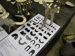 Ein Figurenwald aus dünnem Furnierholz, der aus den Händen der Besucher*innen erwächst. Jedes Detail hat seinen eigenen Namen, da gleichzeitig mit den Figuren auch ein Wort entsteht. 