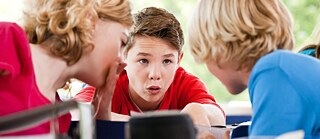Drei Schulkinder kommunizieren im Unterricht