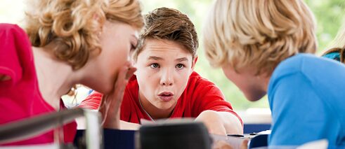 Drei Schulkinder kommunizieren im Unterricht