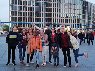 Zuerst haben wir über den Begriff „Netz“ nachgedacht: der Sinn des deutschen Worts „Netz“ und des französischen Wortes „filet“. Dann ist uns die heutige Internetsucht eingefallen.  Die Schüler*innen hatten schon früh an eine Reise durch die Zeit gedacht, weil es früher kein Internet gab. Da sie in Berlin spielen werden, hatten sie eine Parallele mit der Geschichte Berlins gezogen: Vor 30 Jahren fiel die Berliner Mauer.  Danach haben die Schüler*innen selbst ihre Rollen entwickelt, die Kostüme und Accessoires zu Hause zusammengesucht, jede Rolle ist wie eine Karikatur.  Wir haben dann gemeinsam eine treffende Musik für jede Figur gewählt, die Schüler*innen haben sich gefilmt, um ihre Figur vorzustellen. Es war nicht einfach, alles zusammenzubringen und auch die Technik hat uns ein bisschen gestresst, aber am Ende war es sehr toll und humorvoll! 