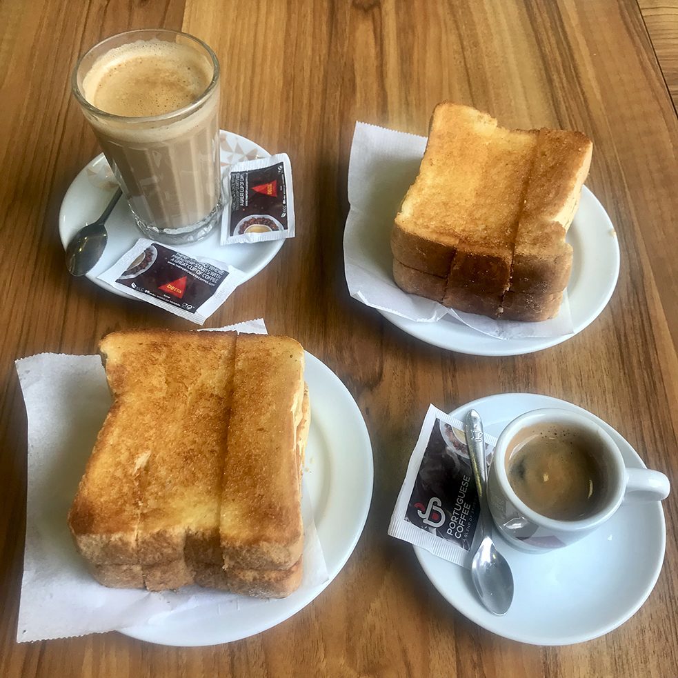 <b>Koffie en toast (Lissabon, Portugal) </b><br><br> Dans ce pays, les gens aiment bien manger, mais le petit-déjeuner est le repas le plus simple de la journée. Par le passé, comme aujourd’hui, un petit-déjeuner typique comprend une "torrada" (pain grillé), avec beaucoup de beurre fondu, et un "galão" (café au lait) ou un "bica" (un espresso). Il est servi au bar d’un café traditionnel. La chose la plus importante à propos du petit-déjeuner est la suivante: il doit pouvoir se manger rapidement.
