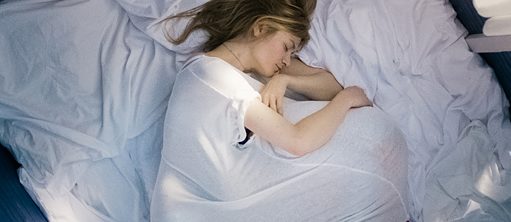 Astrid (gespielt von Julia Jentsch) liegt in einem weißen Nachthemd auf dem Bett. 