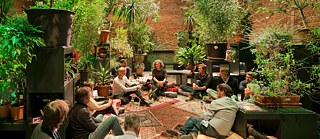 Mehrere Personen sitzen zwischen der Pflanzen der Installation Garden State