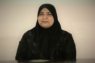 Photo portrait de Feryal al-Ka'abi, une femme d'âge moyen portant un hijab et des vêtements noirs.