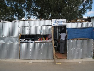 Ein informeller Stand in Diepsloot, einer post-Apartheid Siedlung mit 75% informellen Haushalten, an dem Lebensmittel und Häuser verkauft werden.