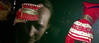 Outi Pieski 2017 in the Finnish National Museum at the end of the exhibition 2017. The horn hat once belonged to her foremother Gáddjá Boine. 