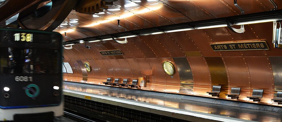 <b>Arts et Métiers (Paris, Frankreich) </b><br><br>Wer den ersten Schritt in die Metrostation Arts et Métiers setzt, begibt sich buchstäblich zwischen die Zahnräder eines Maschinenwerks. Im Bauche dieses mysteriösen „Nautilus“, einer zum Leben erweckten Jules Verne-Phantasie, wartet der Besucher zwischen elf Messing-Bullaugen auf die Metrolinie 11. Ganz in glänzendes Kupfer gekleidet - so entwarf der belgische Künstler François Schuiten 1994 zum 200. Jahrestag des Gewerbemuseums Arts et Métiers, diese einzigartige Metrostation. Das U-Boot-ähnliche Gewölbe versetzt die Besucher in ein technisch-industrielles Universum vergangener Zeiten und erinnert so an das darüber liegende Museum. Attention au départ! - es geht 200 000 Meilen unter das Meer…