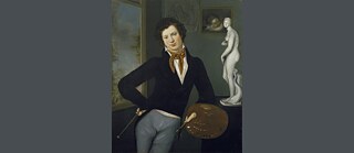 Moritz Daniel Oppenheim est vêtu d’un pantalon gris, d’une chemise blanche, d’une redingote noire et d’un foulard noué autour du cou. Il tient une palette dans sa main et est accoudé à un meuble sur lequel est posée une statue. À l’arrière-plan, il y a des tableaux accrochés au mur.