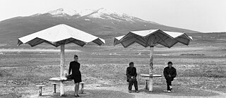 Une femme et deux hommes assis sous des parasols dans un paysage