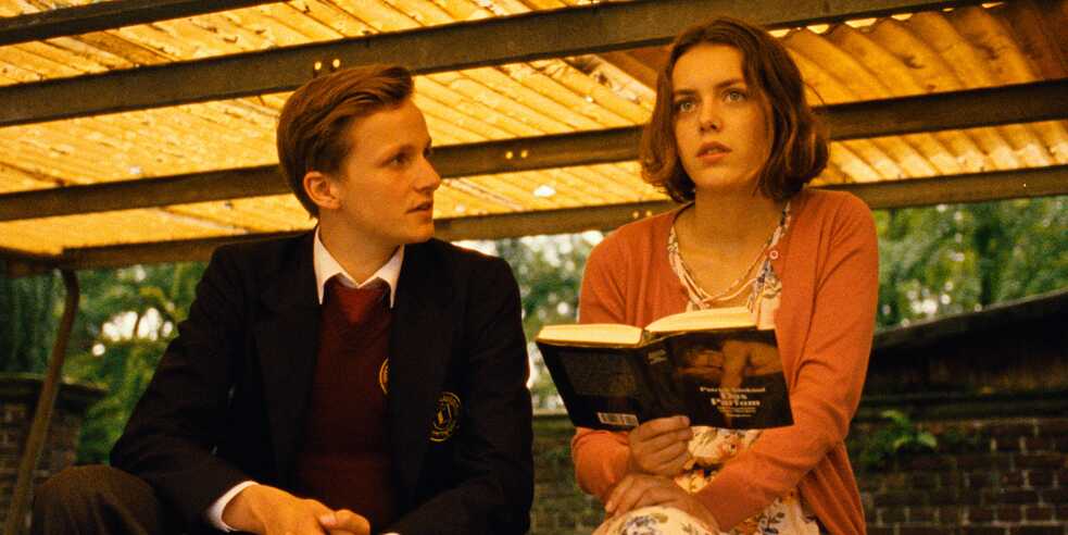 Still frame from the ZDF Series "Parfum - Herzakkord": Outside scene - Moritz (Leon Blaschke) looks at Elena (Valerie Stoll), who holds the book "The Perfume - The Story of a Murderer" by Patrick Süskind in his hands.