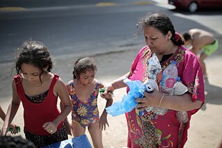 Une femme et deux jeunes filles sur la plage ramassent des ordures.