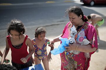 A women and two young girls on the beach collecting rubbish.