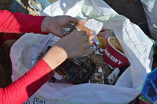 Close-up of the young girls' hand putting rubbish in the bag.