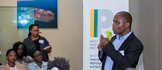 George Juma Ondeng’ heißt das Publikum im Namen der National Museums of Kenya zum Launch des Ausstellungsprojekts „Invisible Inventories“ willkommen.