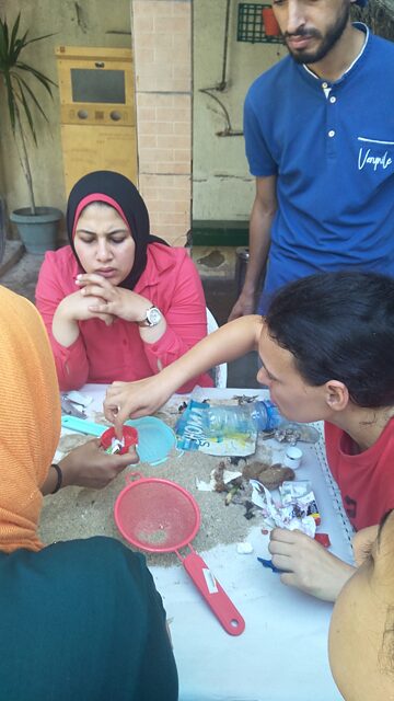 A group of four people sitting around a table examining marine litter.