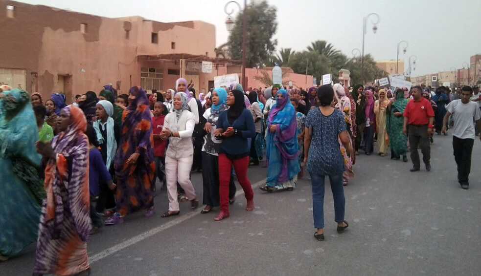 Mehrere Menschen protestieren für ihr Recht auf Wasser. Sie halten ein Plakat mit den Gesichtern und Namen verhafteter Demonstranten.