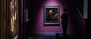 Ein Mann betrachtet ein Gemälde Rembrandts in einer Ausstellung.