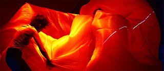 Danseuses avec une bulle de tissus baignée dans une lumière rouge et jaune