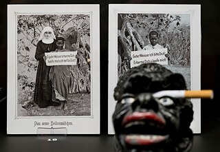 Dos tarjetas postales de las misiones cristianas (1890 y 1914) y un cenicero (1950), como parte de la exposición “Un difícil legado. Rastros coloniales que llegan al presente”, en el Museo Estatal de Hannover, en Baja Sajonia. La exposición presentó más de 200 objetos etnológicos de las antiguas colonias alemanas. 
