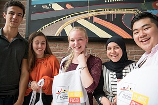 Gastgeber und internationale Gäste präsentieren ihre neuen PASCH-Taschen.