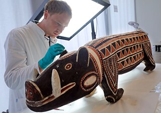 Un restaurador limpia con un fino pincel una figura de madera africana del siglo XIX, durante la visita a la calle de la restauración y una presentación del estudio potencial del complejo museístico Berlín-Dahlem. Desde hace cerca de tres años se está preparando en el Museo de Dahlem la mudanza de aproximadamente 20 mil objetos del Museo Etnológico y del Museo de Arte Asiático al Foro Humboldt.