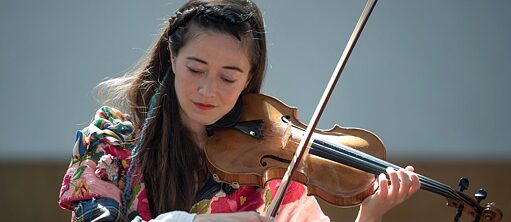 Ayumi Paul bei ihrer Performance mit dem zusammengenähten Kleid, Geige spielend