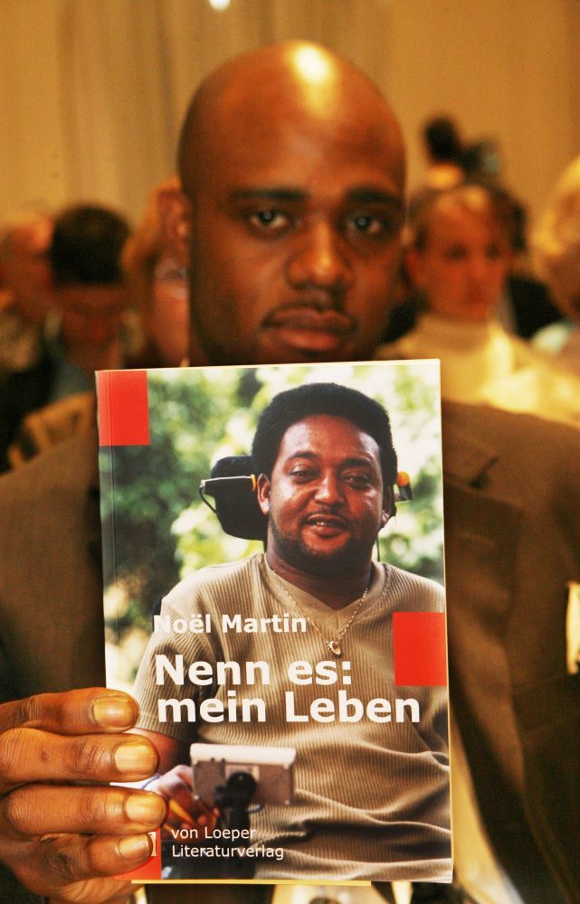 Negus Martin mit dem Buch seines Vaters „Nenn es: mein Leben“. Der farbige Brite Noel Martin war 1996 Opfer eines fremdenfeindlichen Anschlags in der deutschen Gemeinde Mahlow (Teltow-Fläming) geworden. Der im englischen Birmingham lebende 47- Jährige Noel Martin ist seither querschnittsgelähmt. Über einen Fonds fördert er den Jugendaustausch und engagiert sich gegen Rassismus.