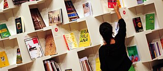 A woman sorts books on a shelf in the pavilion of the host country Brazil at the Book Fair in Frankfurt am Main 2013