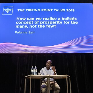 Felwine Sarr 2019 in Wien bei den Tipping Point Talks vor Publikum i dem vollen Saal des Odeon Theaters. 