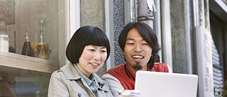 Eine junge Frau und ein junger Mann schauen in einen Laptop. 
