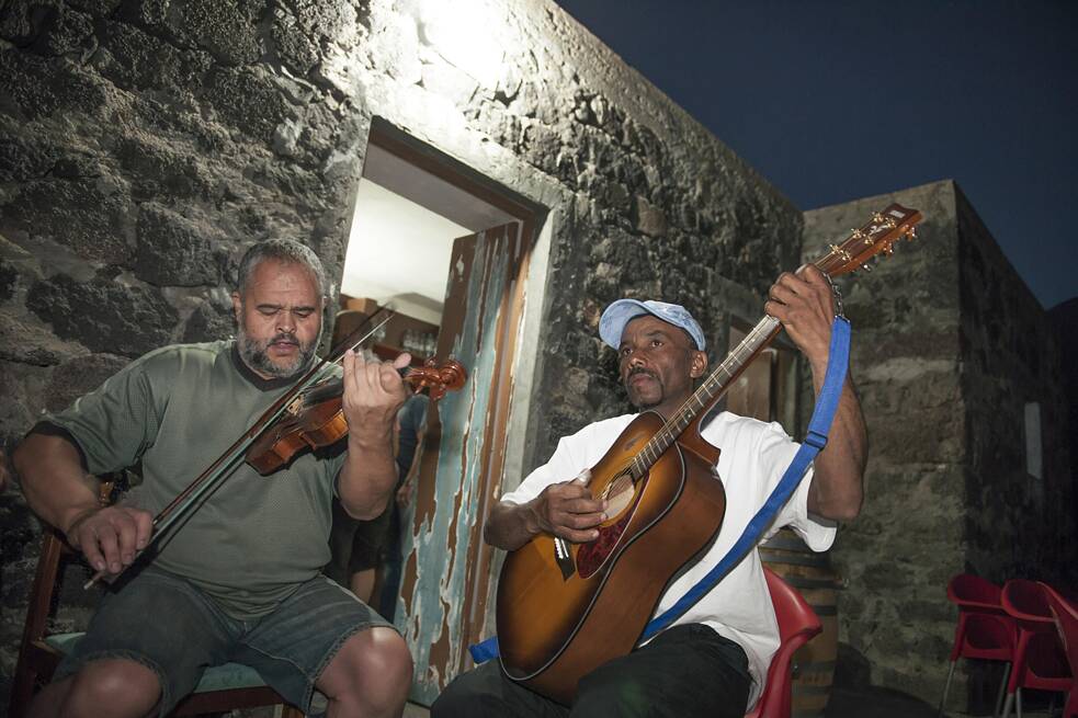 Músicos na Ilha do Fogo, Cabo Verde. A morna, tradicional estilo musical das Ilhas de Cabo Verde, foi incluída na lista do Patrimônio Cultural Imaterial da Unesco em 2019. A decisão foi assim justificada: “A tradição abrange música, canto, poesia e dança. As letras tratam, entre outros, de amor, despedidas e separações, mas também da terra natal e do oceano. Instrumentos típicos do estilo musical são o violão e o violino.”