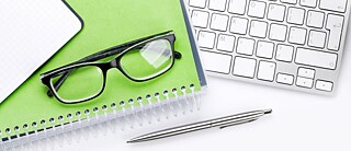 Tastatur, Notizblock und Brille