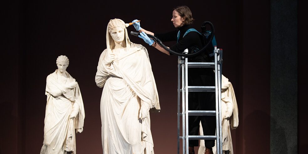 The three marble statues known as the Herculaneum Women are the highlight of the antiquities gallery, here enjoying a final cleaning from the head of the sculpture collection right before the grand reopening. 