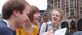 Un jeune homme et deux jeunes femmes qui rigolent devant un bâtiment - Bruxelles