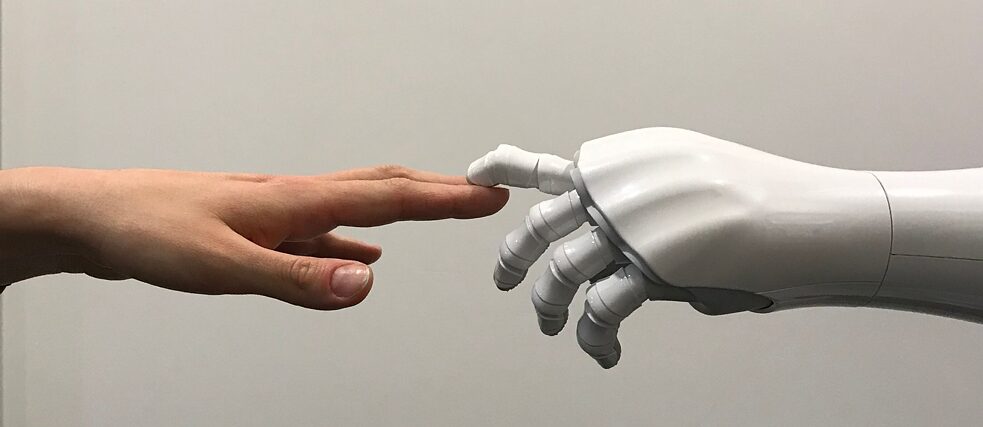 Eine Menschenhand und eine Roboterhand berühren sich.