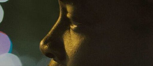 Close-up on a face; you can see the nose and the eye of the person; bright lights on the left side