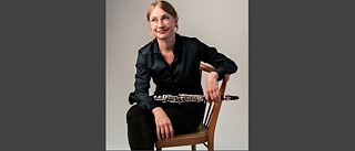 Portrait de Rebecca Trescher, assise sur une chaise, tenant son instrument dans la main gauche
