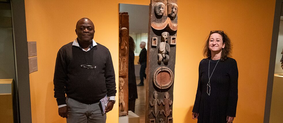 Karin Guggeis (à direita), diretora de projetos do Museu dos Cinco Continentes de Munique, e Albert Gouaffo, coordenador de projetos da Universidade de Dschang (Camarões), ao lado da “Blauer-Reiter-Pfosten” (“Coluna do Cavaleiro Azul”)