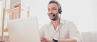 Mann mit Laptop und Headset