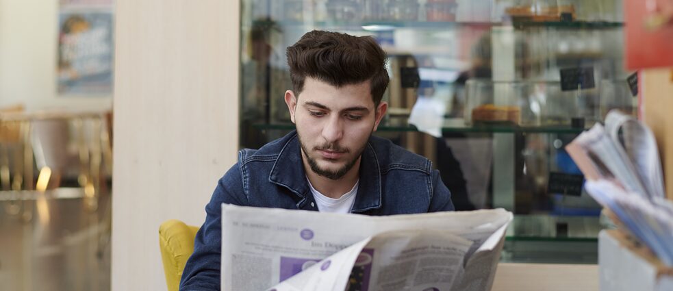 Ein Mann liest Zeitung und sucht nach Stellenangeboten.