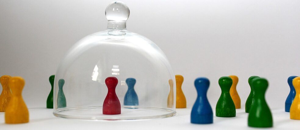 Image de pièces de jeu colorées. L'une est protégée seule sous une cloche de verre.