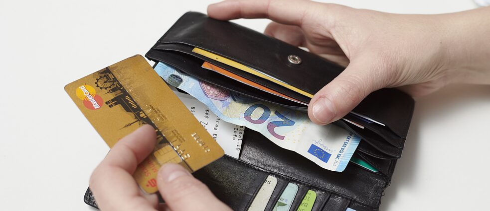 Eine Person zieht eine Kreditkarte aus einem Geldbeutel.