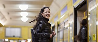 Eine Frau schaut lachend in die Kamera, bevor sie in die U-Bahn steigt.