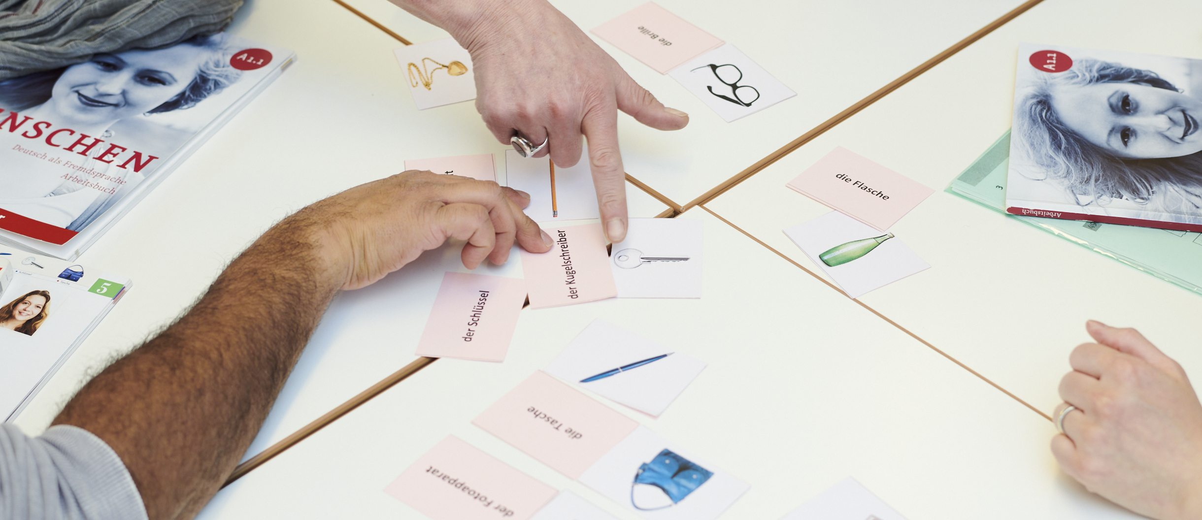 Course participants doing a word exercise on the table. Word cards and textbooks can be seen.