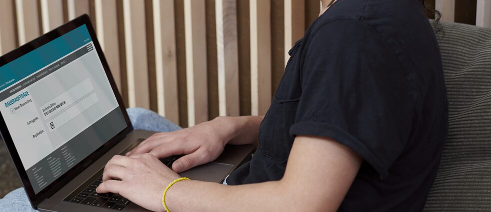 Ein Mann sitzt an einem Laptop und tätigt eine Online-Überweisung.